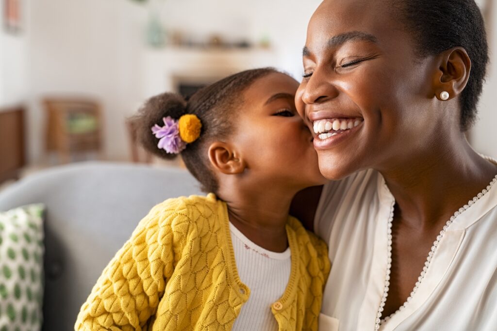 Mom affirmations - beautiful African American mom getting a kiss on cheek from daughter