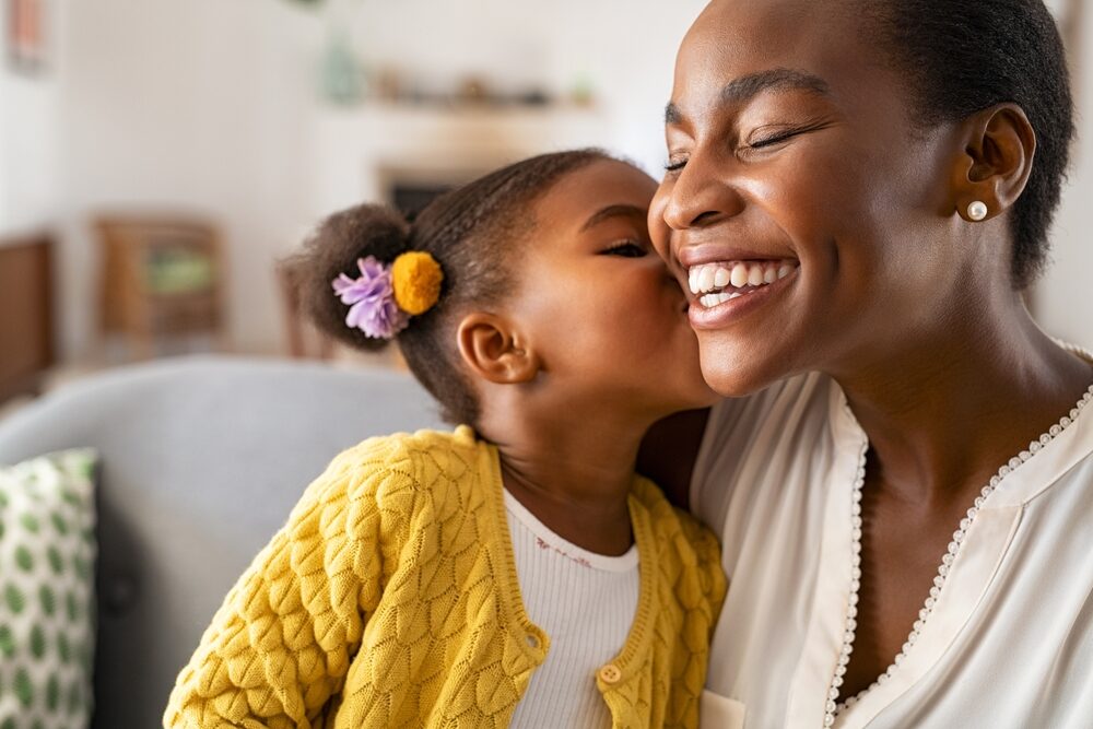 Happy African American mother getting a kiss on cheek from daughter