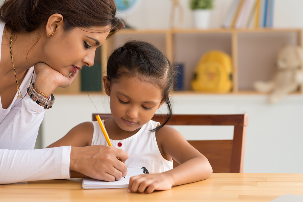 Mom writing in notepad with daughter