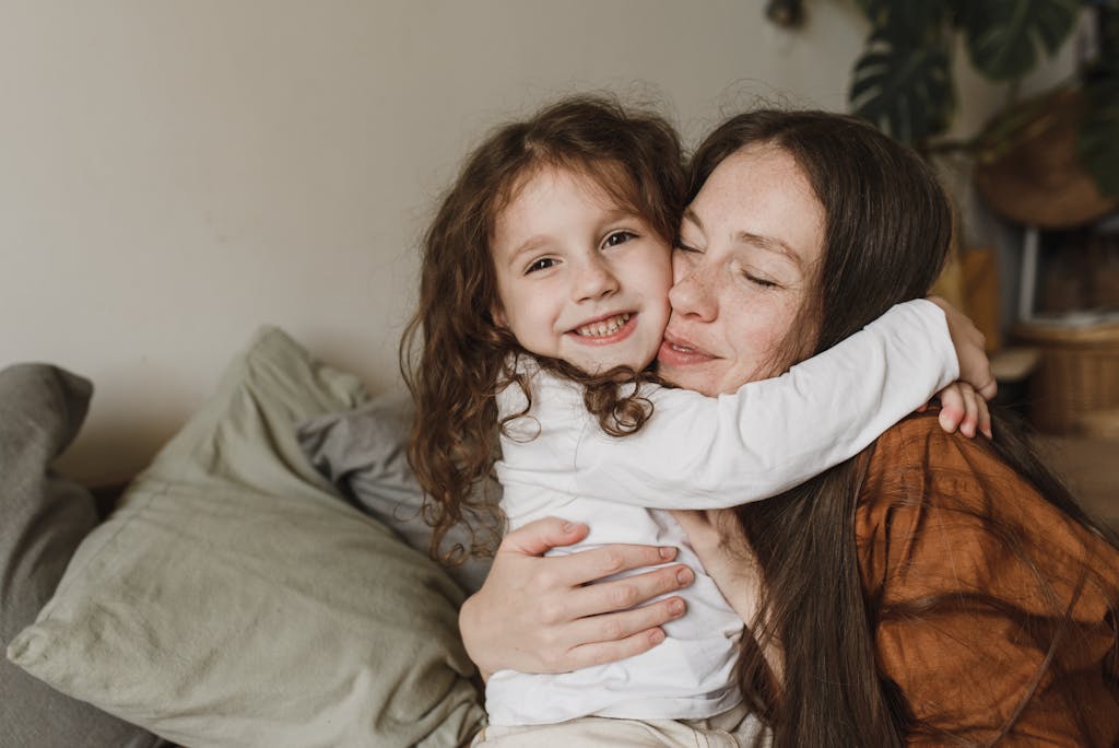 An emotional warm moment between a mother and daughter hugging on the couch indoors.
