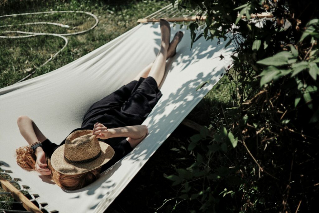 A woman laying in a hammock with a hat on