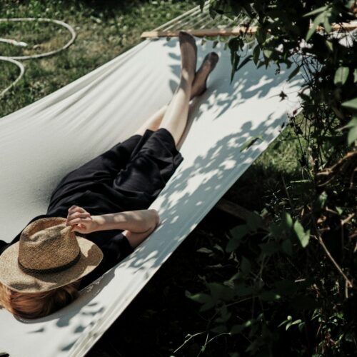 A woman laying in a hammock with a hat on