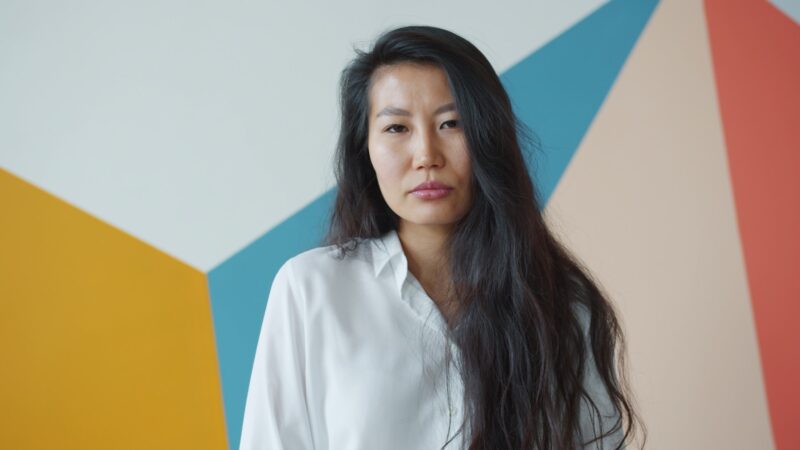 Mentally Checked out in motherhood Woman with long dark hair against colorful wall