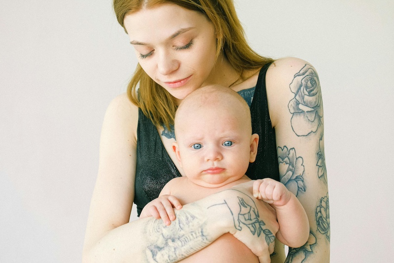identity in postpartum mom with tattoos holding baby.jpg